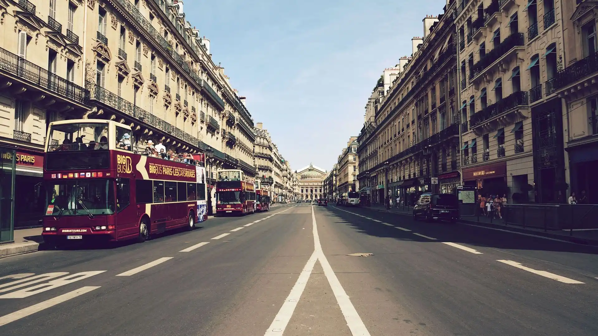 Double-decker sightseeing buses on a Haussmann street in central Paris Double-decker sightseeing buses on a Haussmann street in central Paris