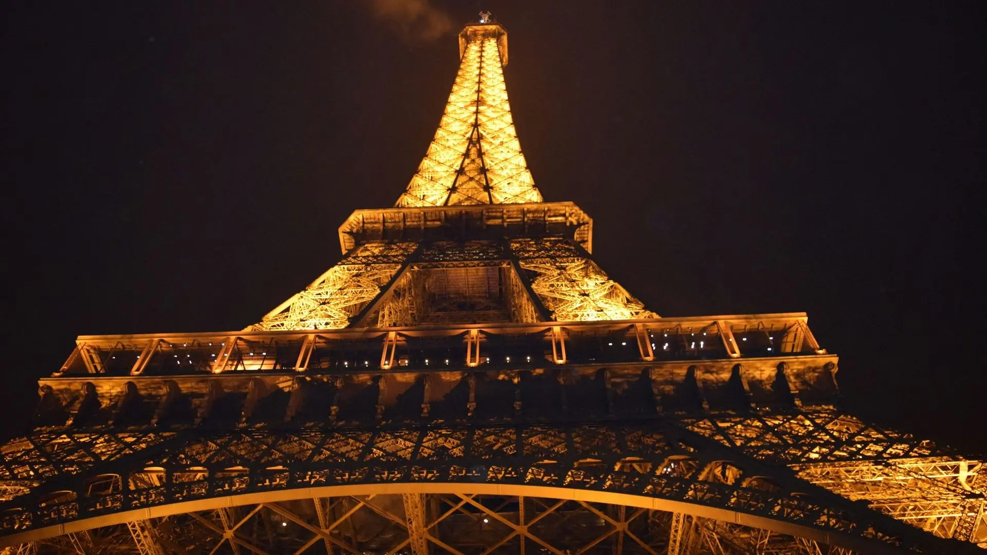 Eiffel Tower lit up gold at night, seen from below Eiffel Tower lit up gold at night, seen from below