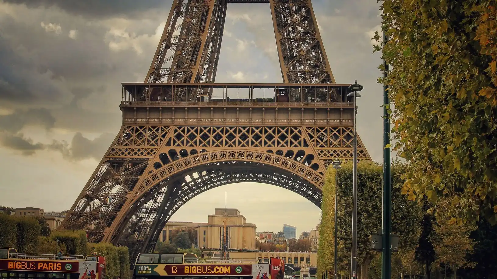 Sightseeing buses on the road at the foot of the Eiffel Tower